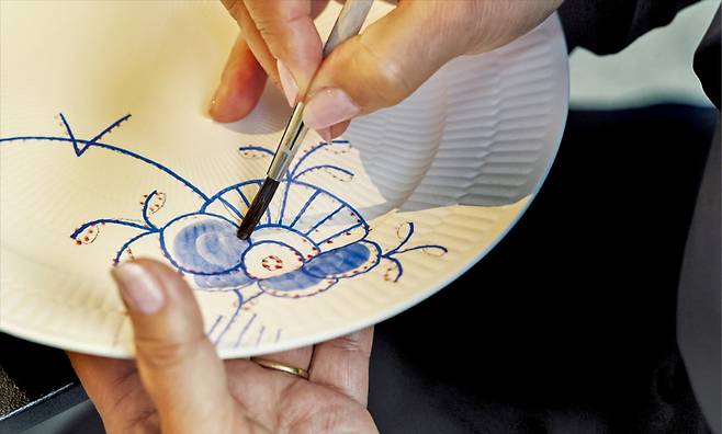 로얄코펜하겐에서 29년 동안 페인팅 작업을 해온 베리카 젤체브 장인이 22㎝ 접시에 블루메가 디자인의 그림을 그려 넣고 있다.  임형택 기자