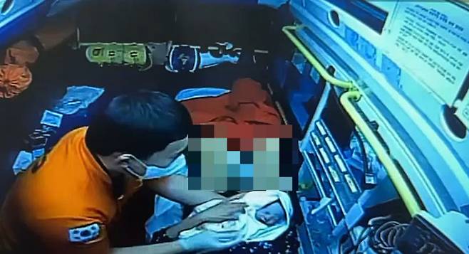 지난 4월 30일 오후 10시 44분께 정선에서 긴급 이송 중이던 119 구급차 안에서 구급대원이 산모의 출산을 도와 건강한 신생아를 들어보이고 있다/사진제공=정선소방서