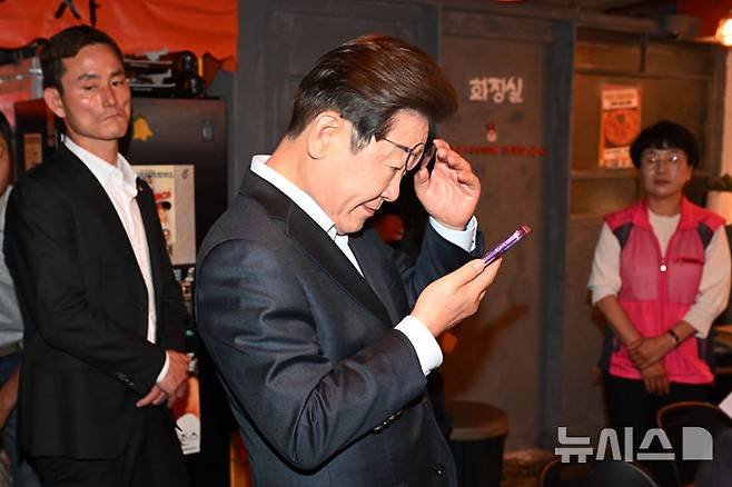 [서울=뉴시스] 조성우 기자 = 이재명 더불어민주당 대선후보가 1일 오후 서울 종로구의 한 포장마차에서 열린 비전형 노동자 간담회를 마친 뒤 휴대전화를 확인하고 있다. 대법원 전원합의체는 이날 이 후보에게 무죄를 선고한 원심 판결을 파기하고 사건을 서울고법으로 돌려보냈다. (공동취재) 2025.05.01. photo@newsis.com