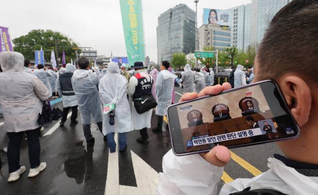 ▲1일 서울 서울 종로구 광화문 동십자각 앞에서 열린 한국노총 주최 '제135주년 세계노동절 전국노동자대회'에서 한 참가자가 더불어민주당 이재명 대선 후보의 공직선거법 사건에 대한 대법원 판결 생중계를 휴대전화로 보고 있다. ⓒ연합뉴스