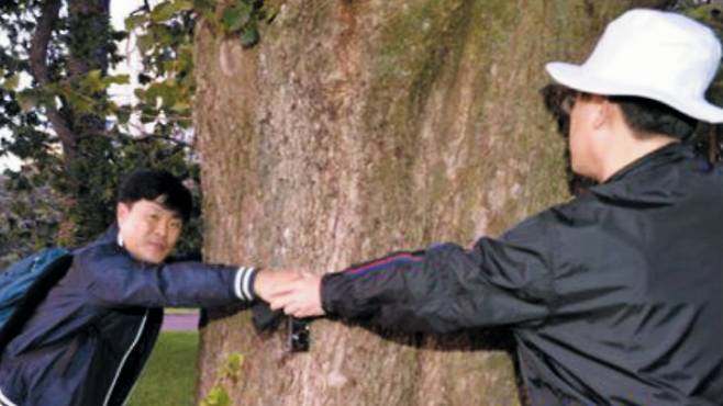 이재명(오른쪽) 더불어민주당 대표와 고(B) 김문기 전 성남도시개발공사 처장이 2015년 1월 호주·뉴질랜드 출장 당시 한 공원에서 손을 맞잡고 있다./국민의힘