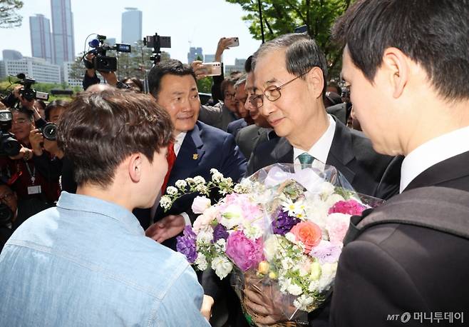 [서울=뉴시스] 고승민 기자 = 한덕수 전 국무총리가 2일 서울 여의도 국회 소통관에서 대선 출마 기자회견을 마친 뒤 건물을 나서던 중 한 청년으로부터 꽃을 받고 있다. 2025.05.02. kkssmm99@newsis.com /사진=고승민