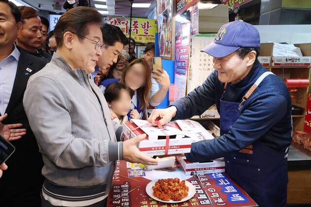 이재명 더불어민주당 대통령 후보가 3일 ‘동해안 벨트’ 첫 방문지인 강원도 속초시 중앙재래시장에서 닭강정을 구입하며 상인과 대화하고 있다. 연합뉴스