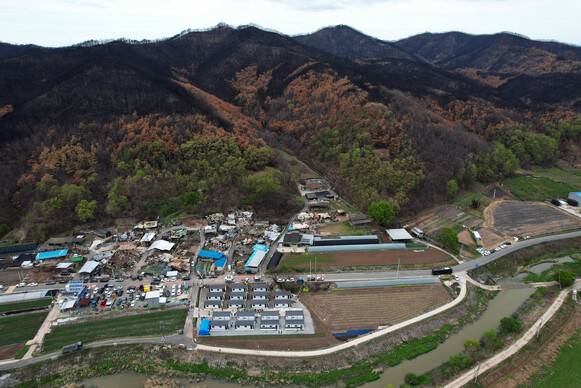 2025년 4월23일 오후 경북 안동시 일직면 명진리에서 산불로 집을 잃은 주민을 위한 이동주택(아래쪽) 입주식이 열리고 있다. 산 아래쪽에 불탄 집들이 보인다. 무인기를 띄워 찍었다.