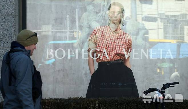 [서울=뉴시스] 고범준 기자 = 4일 한 시민이 서울의 한 백화점 앞에 설치된 보테가베네타 광고판 앞으로 지나가고 있다. 명품 브랜드 보테가베네타(Bottega Veneta)는 일부 가방 및 지갑 제품 중심으로 약 10% 가격을 올린다고 밝혔다. 2025.02.04. bjko@newsis.com