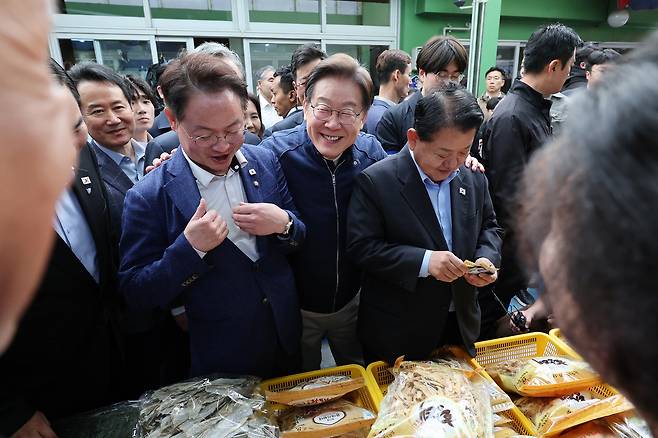 민심을 청취하는 '경청 투어'에 나선 이재명 더불어민주당 대선후보가 2일 오후 강원도 인제군 원통전통시장에서 건어물 가게를 방문해 황태채를 맛본 뒤 허영(왼쪽), 김병주 의원에게 구입을 권하고 있다.&nbsp; &nbsp;뉴시스