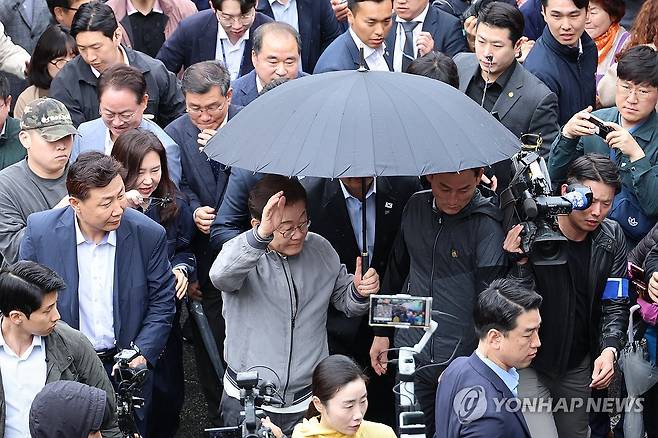 이재명 후보, 잇따르는 피습 제보에 경호 강화 (속초=연합뉴스) 김주성 기자 = 더불어민주당 이재명 대선 후보가 '골목골목 경청투어' 사흘째인 3일 '동해안벨트' 첫 방문지인 강원도 속초시 중앙재래시장에서 비가 그쳤음에도 우산을 쓴 채로 두터운 경호막에 둘러싸여 도민들을 향해 인사하고 있다. 
    이날 이 후보 측은 SNS를 통해 "후보에 대한 피습 모의 제보가 잇따르고 있다. 이에 따라 지금부터 후보의 대인 접촉이 어려운 상황이다. 너른 양해 부탁드린다"라고 공지했다. 2025.5.3 utzza@yna.co.kr