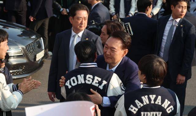 윤석열(가운데) 전 대통령이 지난달 11일 서울 용산구 한남동 대통령 관저를 나와 자택으로 이동하던 중 '과잠'을 입은 대학생 지지자들과 포옹하고 있다. 사전에 대통령실이 기획한 연출이라는 지적도 나왔다. 뉴스1