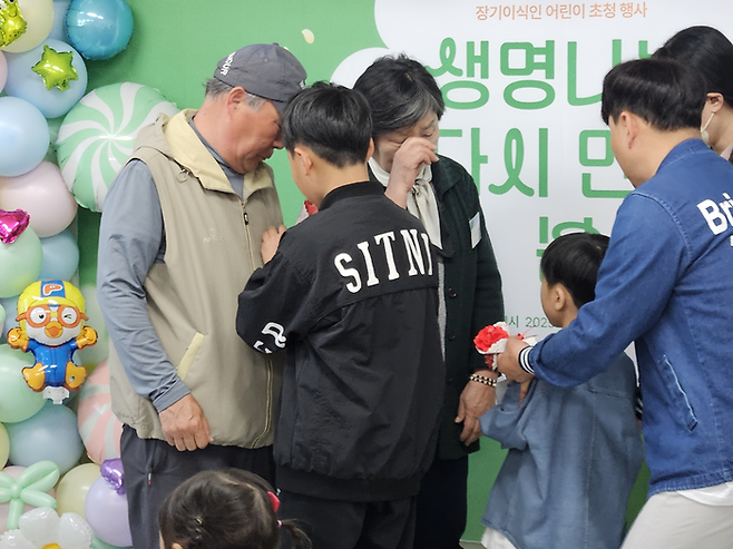 지난 1일 오전 서울 사랑의장기기증운동본부에서 강윤호 군(8) 가족이 도너패밀리에게 직접 만든 카네이션을 달아주고 있다. [지혜진 기자]
