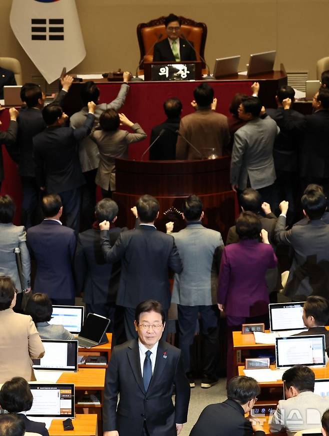 [서울=뉴시스] 권창회 기자 = 이재명 더불어민주당 대표가 27일 오후 서울 여의도 국회에서 열린 제420회국회(임시회) 제2차 본회의에서 국무총리(한덕수) 탄핵소추안 투표를 마친뒤 항의하는 국민의힘 의원들 뒤로 미소 지으며 이동하고 있다. 2024.12.27. kch0523@newsis.com