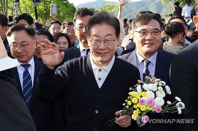지지자들에게 인사하는 이재명 후보 (제천=연합뉴스) 김주성 기자 = 더불어민주당 이재명 대선 후보가 '골목골목 경청투어' : 단양8경편'에 나선 4일 충북 제천군 의림지를 찾아 한 지지자가 준 꽃을 들고 인사하고 있다. 2025.5.4 utzza@yna.co.kr