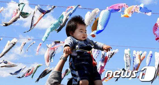 29일 일본 가나가와(神奈川)현 사가미하라(相模原) 소재 공원에서 한 아버지가 아이를 들어올리고 있다. 위에는 고이노보리가 걸려 있다. 고이노보리는 5월 5일 어린이날에 종이나 천 등으로 잉어 모양을 만들어 깃발처럼 장대에 높이다는 일본의 풍습으로, 아이가 건강하게 자라길 바라는 마음이 담겨 있다. ⓒ AFP=뉴스1 ⓒ News1 최종일 기자