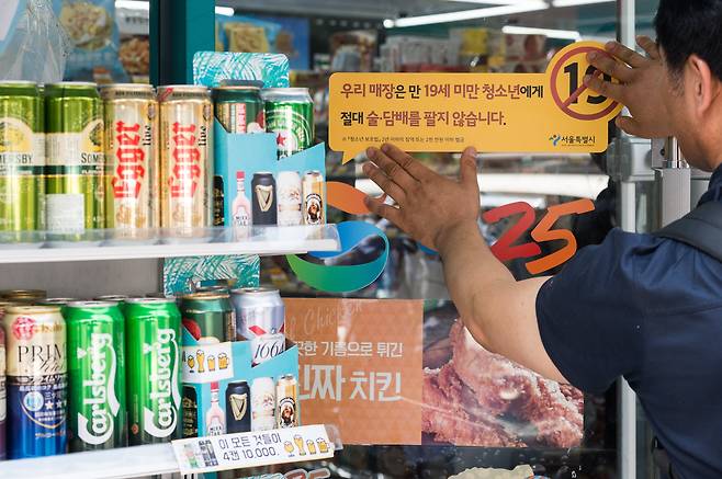 서울 종로구의 한 편의점에 청소년 대상 술·담배 판매금지 경고문구 스티커를 부착하고 있는 모습. /뉴스1