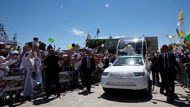 프란치스코 교황이 2014년 베들레헴에서 미사를 집전하기 위해 포프모빌을 타고 도착하고 있다.