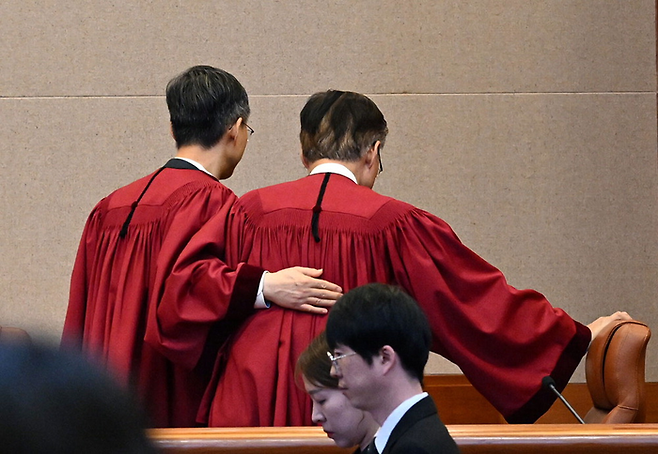 헌법재판소 대심판정에서 윤석열 대통령에 대해 파면 결정을 선고한 뒤 김형두 헌법재판관의 어깨를 두드리며 문형배 헌법재판소장 권한대행(왼쪽)이 퇴장하고 있다. [사진 출처 = 사진공동취재단]