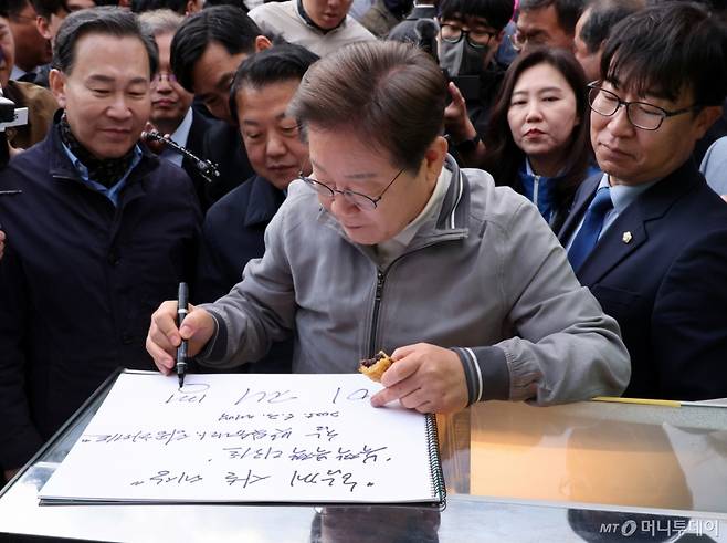 [태백=뉴시스] 조성우 기자 = 민심을 청취하는 '경청 투어'에 나선 이재명 더불어민주당 대선후보가 3일 강원도 태백시 장성중앙시장에서 잉어빵을 파는 상인에게 방명록을 남기고 있다. 2025.05.03. xconfind@newsis.com /사진=조성우