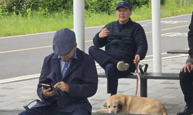 윤석열 전 대통령이 5일 서울 동작대교 부근 한강공원에서 반려견과 함께 산책을 하다 쉬는 모습이 시민 카메라에 담겼다. 온라인 커뮤니티 캡처
