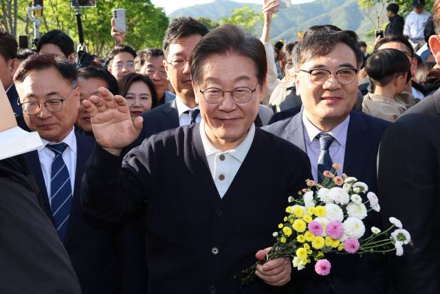 이재명 더불어민주당 대선 후보가 '골목골목 경청투어' : 단양8경편'에 나선 4일 충북 제천군 의림지를 찾아 한 지지자가 준 꽃을 들고 인사하고 있다. 연합뉴스