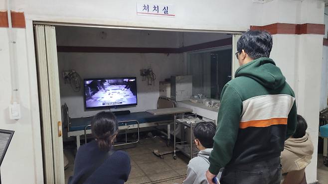 병원을 찾은 김동호(45) 씨 가족이 응급실 옆 처치실에서 상영되고 있는 병원 관계자 증언 영상을 시청하고 있다. /박정석 기자