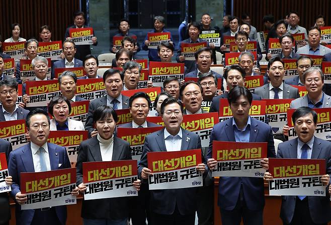 더불어민주당 박찬대 원내대표를 비롯한 의원들이 4일 국회에서 열린 긴급 의원총회에서 대법원 규탄 팻말을 들고 구호를 외치고 있다. /연합뉴스