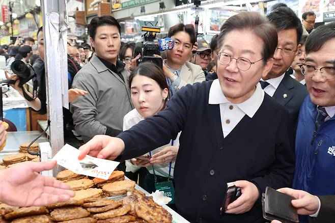 더불어민주당 이재명 대선 후보가 '골목골목 경청투어' : 단양8경편'에 나선 4일 충북 단양군 단양구경시장에서 떡갈비를 사먹으면서 지역화폐를 사용하고 있다. /연합뉴스