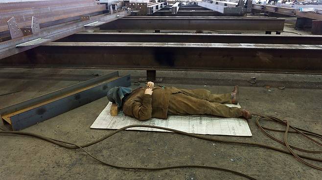 중국에서 온 이 모씨가  1월 한겨울의 차가운  땅 위에 누워 점심 식사 후 쉬고 있다. 2015년 /사진가 심학철