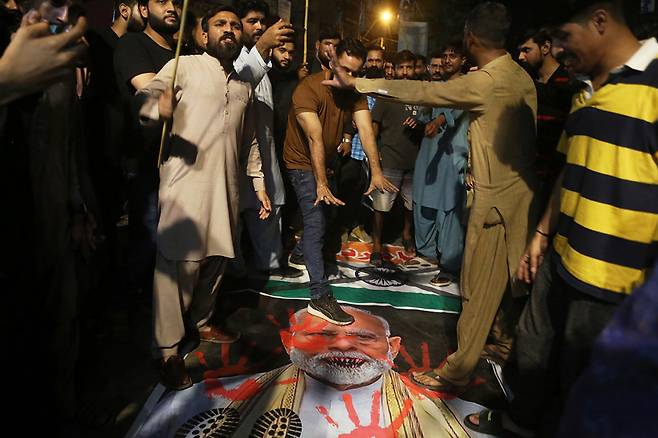 7일(현지 시간) 파키스탄 하이데라바드에서 인도의 미사일 공격에 분노한 시민들이 나렌드라 모디 인도 총리의 사진과 인도 국기를 발로 밟고 있다. 이날 인도가 파키스탄령 카슈미르 등에 미사일을 발사해 26명이 숨졌다. 파키스탄도 즉각 인도령 카슈미르 등에서 미사일 보복 공격에 나서 10명이 사망했다. 사실상 핵 보유국인 두 나라의 무력 충돌이 전면전 직전으로 치닫고 있다. 하이데라바드=AP 뉴시스