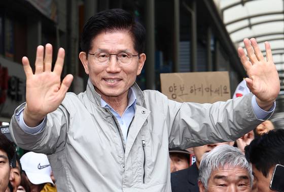 김문수 국민의힘 대통령 후보가 6일 경북 포항시 죽도시장에서 시민들을 향해 인사하고 있다.  뒷편에는 한 지지자가 '양보 하지 마세요'라고 적힌 종이를 들어보이고 있다. 뉴스1