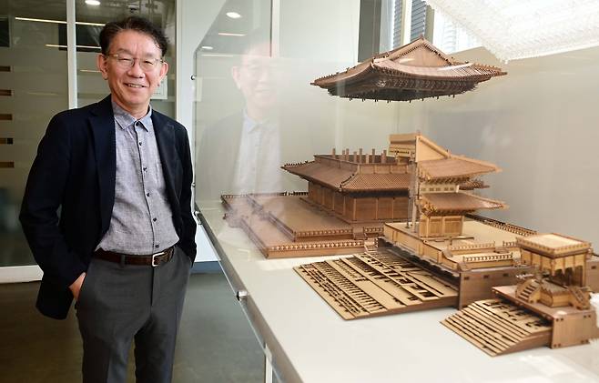 Jeon Bong-hee, an architecture professor at Seoul National University, poses for a photo in front of a model showing the structure of Geunjeongjeon, the main hall of Gyeongbokgung, at Seoul National University on April 28. The model of the structure was created with the design program his research team created in 2021. (Lee Sang-sub/The Korea Herald)