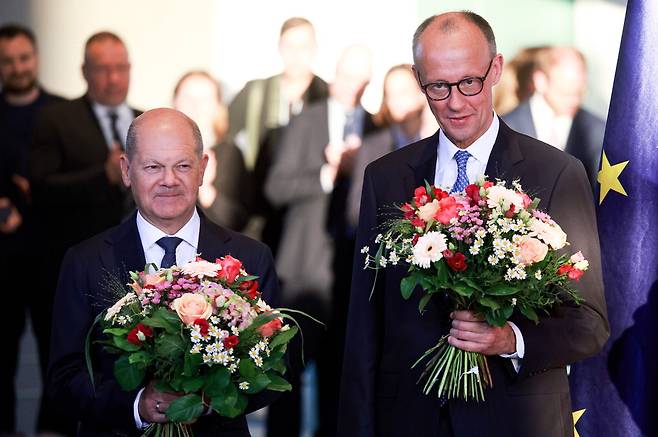 독일 신구 총리6일(현지시간) 독일 베를린 총리 관저에서 열린 총리 이임식에서 프리드리히 메르츠 신임 총리(오른쪽)와 올라프 숄츠 전 총리(왼쪽)가 꽃다발을 들고 기념촬영을 하고 있다.  EPA연합뉴스