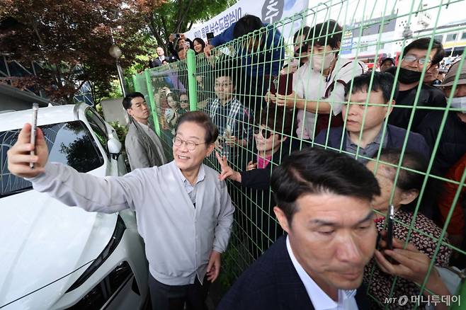 [전주=뉴시스] 조성봉 기자 = 민심을 청취하는 '경청 투어'에 나선 이재명 더불어민주당 대선후보가 7일 전북 전주시 완산구 풍남문 인근에서 철조망 너머에 있는 시민들과 셀카를 찍고 있다. 2025.05.07. suncho21@newsis.com /사진=조성봉