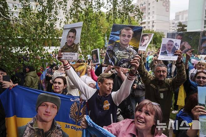 [우크라이나=AP/뉴시스] 6일(현지 시간) 우크라이나의 장소 미공개 지역에서 러시아와의 포로 교환을 통해 석방된 우크라이나 군인들에게 실종되거나 억류 중인 군인 가족들이 사진을 보여주며 생사를 확인하고 있다. 2025.05.07.