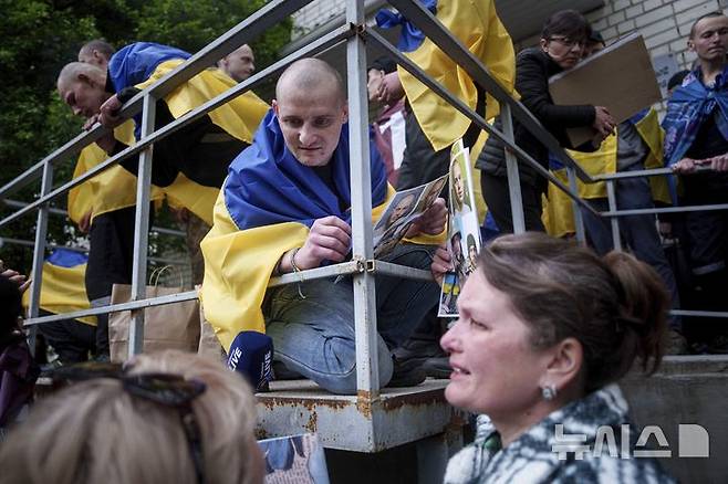 [우크라이나=AP/뉴시스] 6일(현지 시간) 러시아와의 포로 교환을 통해 석방된 우크라이나 군인이 장소가 알려지지 않은 곳에 도착해 동료 군인의 가족과 대화하고 있다. 양국은 이날 205명의 포로를 교환했다. 2025.05.07.