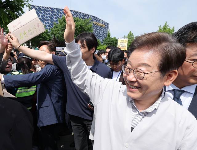 ▲더불어민주당 이재명 대선 후보가 '골목골목 경청투어:국토종주편'에 나선 7일 전북 전주시 풍남문 앞 광장에서 지지자가 든 공판 연기 환영 팻말을 지나고 있다. 이날 서울고등법원은 오는 15일 예정됐던 이 후보의 공직선거법 위반 혐의 사건 파기환송심 첫 공판을 오는 6월 18일로 연기했다. ⓒ연합뉴스