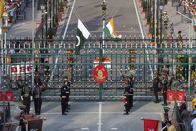 파키스탄 라호르 인근 파키스탄과 인도 국경의 합동 초소인 와가에서 검은 옷을 입은 파키스탄 레인저스 군인들과 문 뒤의 인도 국경보안군 군인들이 일일 종무식에서 국기를 내리고 있다. AP 연합뉴스