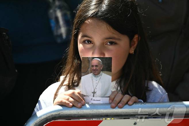 프란치스코 교황의 장례 미사에서 한 여성 어린이가 프란치스코 교황 사진을 들고 있는 모습. ⓒ AFP=뉴스1