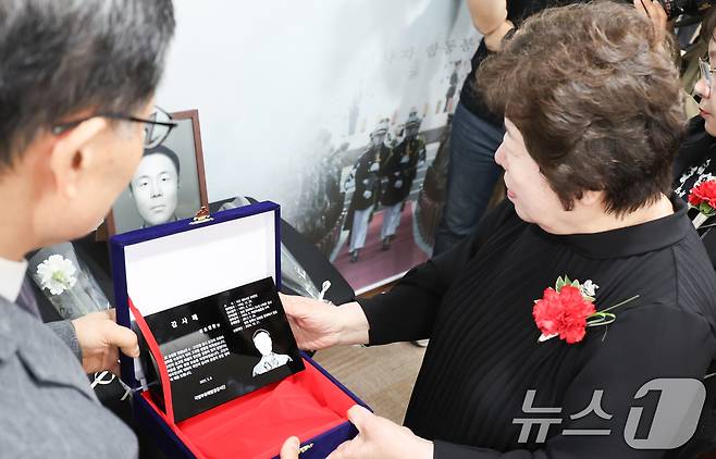 8일 서울 동작구 국방부유해발굴감식단에서 열린 6·25전사자 유해 얼굴복원 유가족 초청행사에서 故 송영환 일병의 딸인 송재숙 씨가 영정에 감사패를 놓고 있다. 2025.5.8/뉴스1 ⓒ News1 허경 기자