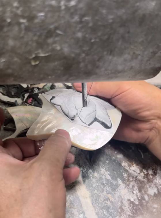 An artisan works on the mother-of-pearl inlay on Jennie’s glossy black and white tube top in the “Seoul City” music video. [LEJE]