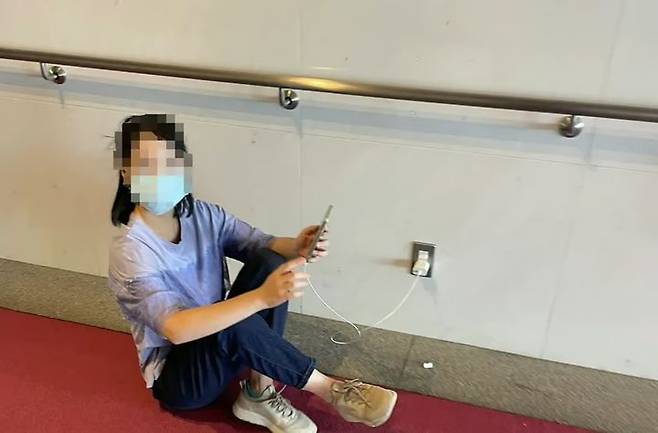[뉴시스]중국인으로 추정되는 한 여성이 공공장소 콘센트를 이용해 휴대전화를 충전하는 모습. (사진=QQ.com) *재판매 및 DB 금지