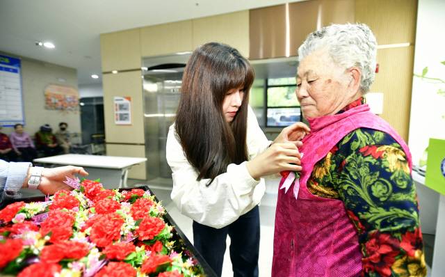 ▲ 어버이날인 8일 화천군 화천읍 신읍리 공공실버주택 직원들이 입소자 가슴에 카네이션을 달아드리고 있다.