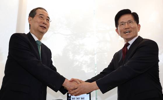 Han Duck-soo, left, an independent presidential candidate, shakes hands with Kim Moon-soo, the presidential candidate of the conservative People Power Party, in a restaurant in Jongno District, central Seoul, on May 7. [YONHAP]