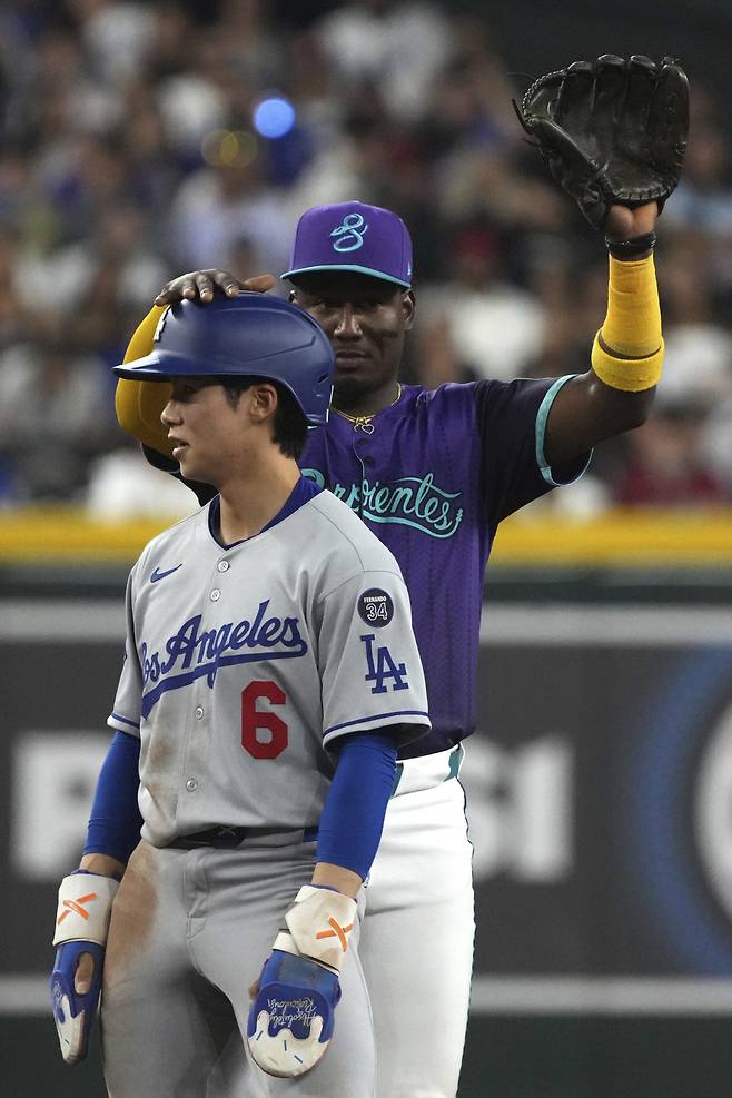 LA 다저스 김혜성이 11일(한국시각) 애리조나 다이아몬드백스전에서 5회 2루수 땅볼을 치고 선행주자 아웃으로 출루한 뒤 상대 선발 코빈 번스의 견제 회수 제한 위반으로 2루로 자동진루하자 상대 유격수 헤랄도 페르도모가 헬멧을 만지며 장난을 치고 있다. AP연합뉴스
