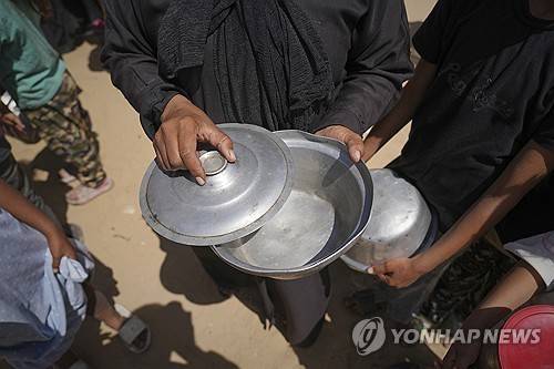 식량 바닥 난 가자지구 (가자지구 칸유니스 AP=연합뉴스) 2025년 5월 9일 가자지구 남부 칸유니스의 한 급식소에서 식재료가 바닥나자 한 여성이 비어 있는 그릇을 열어 보고 있다. (AP Photo/Abdel Kareem Hana) 2025.5.10.