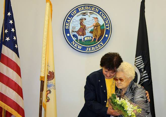 위안부 피해 이옥선 할머니, 미국 버겐카운티 기림비 방문 (뉴욕=연합뉴스) 일본군 위안부 피해자인 이옥선 할머니가 2013년 7월 15일(현지시간) 미국의 지방 정부가 직접 만든 버겐카운티의 위안부 기림비를 방문했다. 이 기림비는 미국 뉴저지주 버겐카운티 해켄색의 버겐카운티 법원 앞 '메모리얼 아일랜드'에 있다. 사진은 캐서린 도너번 버겐카운티장이 이 할머니에게 꽃을 전달하고 안아주는 모습. 2013.7.16 [연합뉴스 자료사진. 재판매 및 DB 금지]