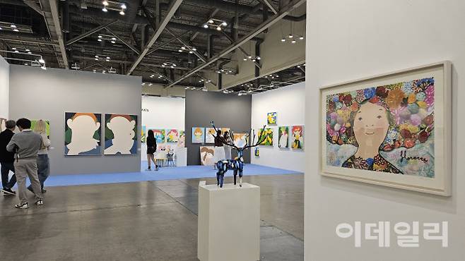 ‘아트부산 2025’ 전경. 부산에 근거지를 둔 갤러리아리랑 부스와 소울아트스페이스 부스가 마주보고 있다. 오른쪽으로 소울아트스페이스에서 건 에바 알머슨 작가의 ‘만개’(2024)가 복도 건너편으로는 변웅필 작가의 ‘누군가’(2025) 연작이 보인다(사진=오현주 문화전문기자).