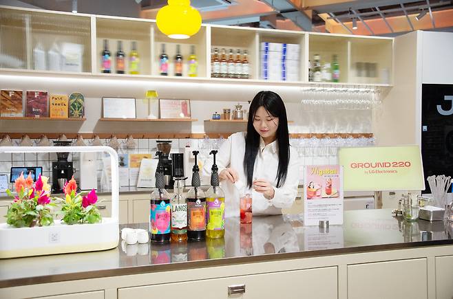 LG전자가 고객경험 공간 ‘그라운드 220’에서&nbsp;다양한 주방 가전으로 직접 디저트를 만들고, 다채로운 콘텐츠와 함께 즐기는 새로운 고객경험 공간을 선보인다.&nbsp;사진은 LG전자 모델이 다양한&nbsp;음료, 과일과 식물생활가전 ‘틔운’에서 키운 허브 등을 이용해 나만의 음료를 만드는 모습.&nbsp; LG전자 제공