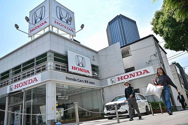 13일 일본 도쿄 중심가의 한 거리에서 보행자들이 자동차 대리점 앞을 지나가고 있다. (사진=AFP)