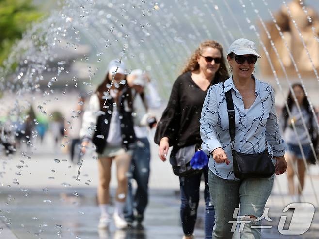 대체로 맑고 포근한 '초여름 날씨'를 보인 12일 오후 서울 광화문광장 분수터널에서 외국인 관광객들이 더위를 식히고 있다. 2025.5.12/뉴스1 ⓒ News1 황기선 기자