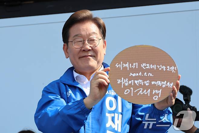 이재명 더불어민주당 대통령 후보가 제21대 대통령 선거 공식 선거운동 첫날인 12일 오후 경기 화성시 동탄 센트럴파크 음악분수중앙광장에서 '세계1위! 반도체 강국도약!'이라고 쓴 반도체 웨이퍼를 들어 보이고 있다. (공동취재) 2025.5.12/뉴스1 ⓒ News1 안은나 기자