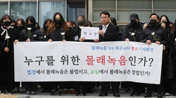 웹툰 작가 주호민씨 아들을 학대한 혐의로 1심에서 벌금 200만원 선고유예를 받은 특수교사 A씨와 김기윤 경기도교육감 고문변호사가 지난해 2월 수원지방법원에서 기자회견을 하기 전 항소장을 들고 있다. 뉴스1